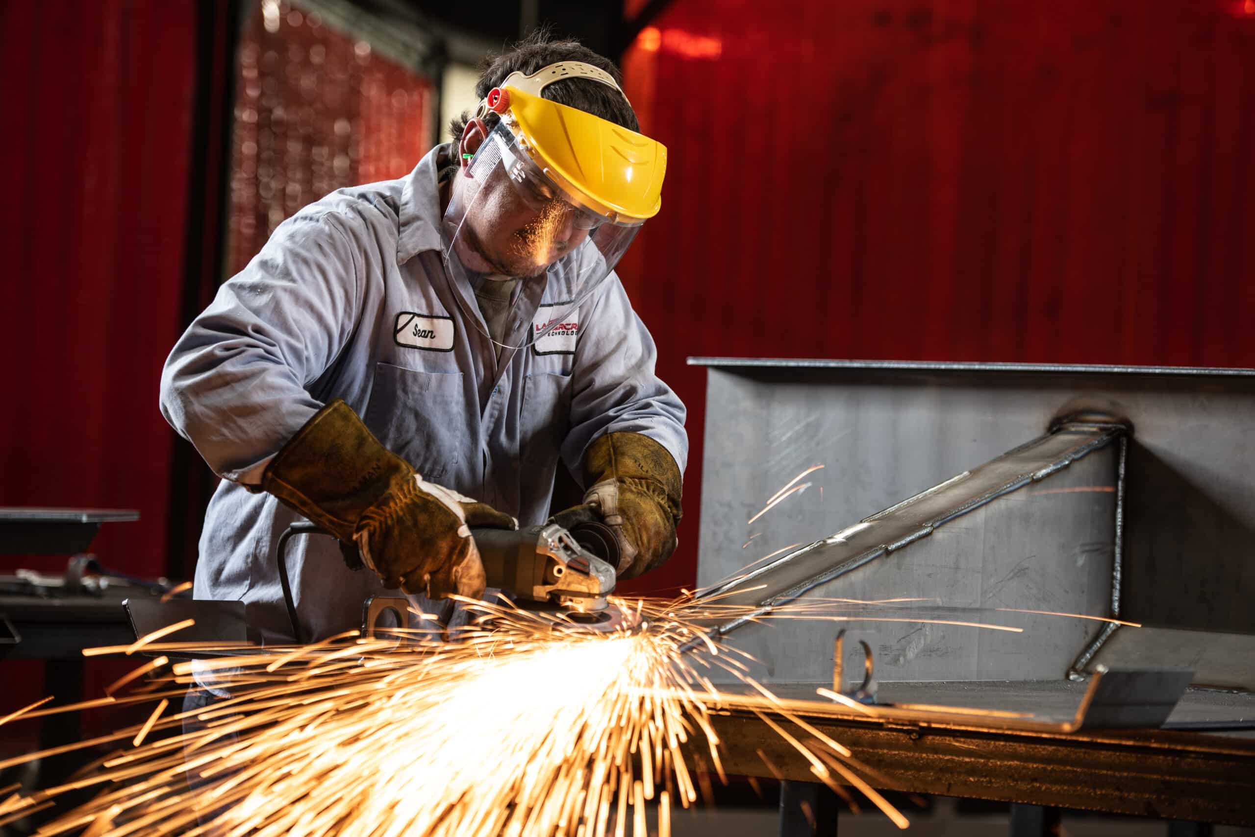 Laser Craft Tech employee using a metal grinder as sparks fly