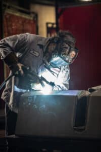 Laser Craft Tech employee welding steel in dramatic lighting