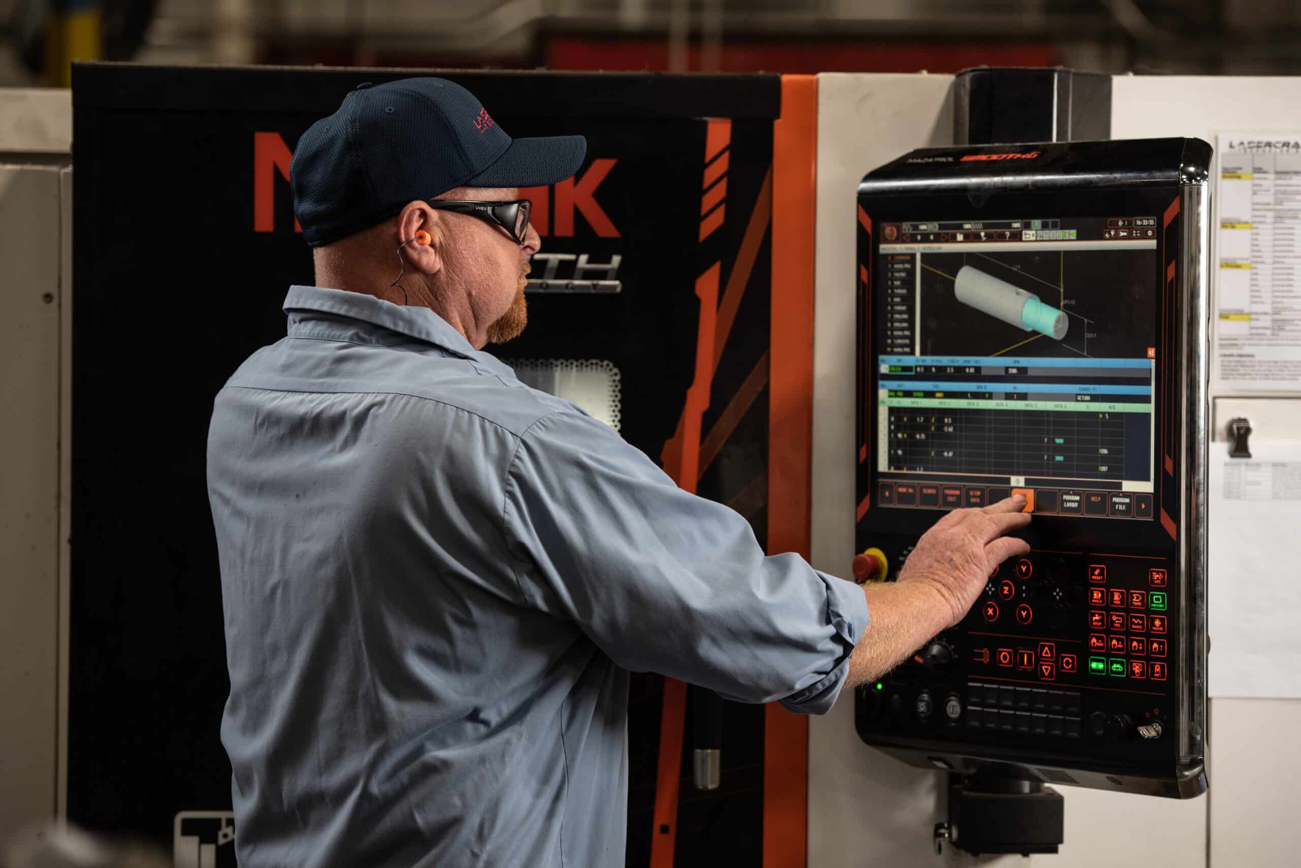 Laser Craft Tech employee operates a digital control panel on a fabrication machine
